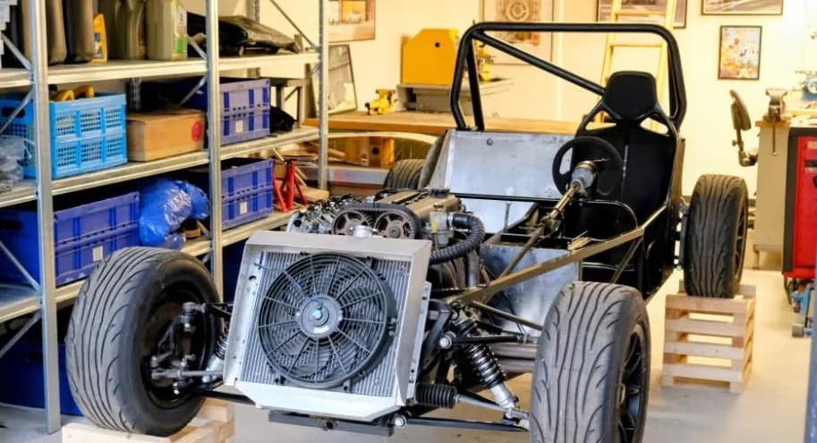 Rechte hoek op het chassis met werkplaats en race-artwork op de achterwand. Widebody-vering en 13-inch Team Dynamics duidelijk zichtbaar.