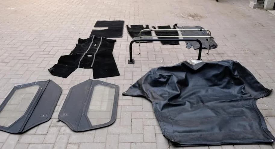 Losse interieurdelen op de oprit: tapijten, deuren, rolbeugel en soft top.