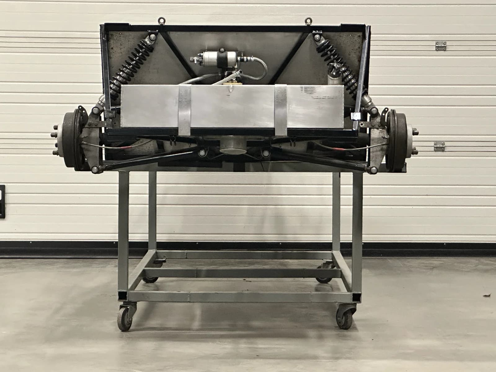 Achteraanzicht van hetzelfde chassis. Trommels van de achterremmen, dempers, achteras en brandstofbuffer in zicht.